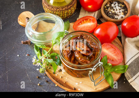 Sonnengetrocknete Tomaten mit Olivenöl in einem Glas auf schwarzen Stein oder Beton. Kopieren Sie Platz. Stockfoto