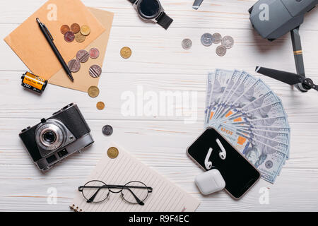 Kamera, touristischen Karten, Reisepass, Kopfhörer, Geldbörse mit Kreditkarten, Dollar, Banknoten und Münzen auf den weißen Schreibtisch. Reisen Hintergrund. Touristische essen Stockfoto