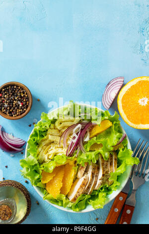 Diätmenü. Gesunden Salat mit Huhn, Ei Pfannkuchen, Orange, grüner Salat und Dressing vinaigrette auf einem blauen Tisch aus Stein. Ansicht von oben flach Hintergrund. Stockfoto