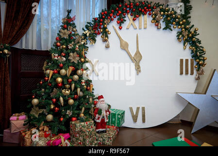 Weihnachtsbaum mit Geschenken und einer Uhr mit сountdown bis Mitternacht. Stockfoto