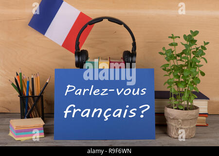 Konzept des Lernens der französischen Sprache - Papier mit Text "Parlez-vous Français?' (Parlez vous Francais?), Flagge der Frankreich, Bücher, Kopfhörer, Bleistifte Stockfoto