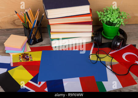 Sprachen lernen Konzept - leeres Papier, Flaggen, Bücher, Kopfhörer, Bleistifte auf hölzernen Hintergrund Stockfoto