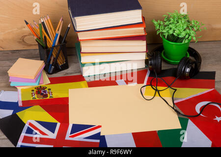 Sprachen lernen Konzept - leeres Papier, Flaggen, Bücher, Kopfhörer, Bleistifte auf hölzernen Hintergrund Stockfoto