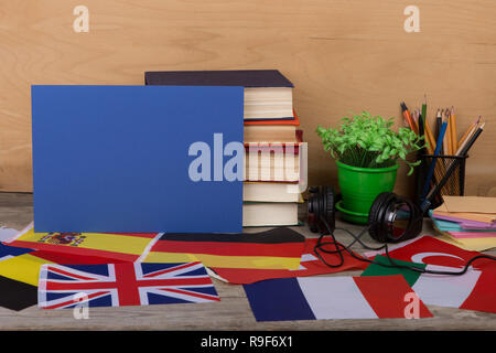 Sprachen lernen Konzept - leeres Papier, Flaggen, Bücher, Kopfhörer, Bleistifte auf hölzernen Hintergrund Stockfoto