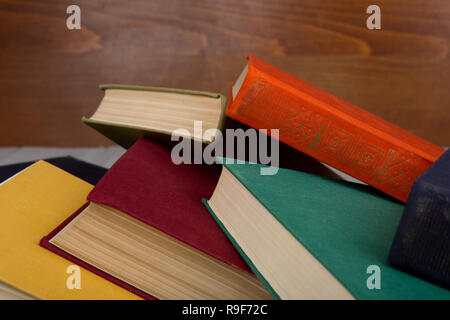 Zurück zu Schule und Bildung Konzept-Heap-bunten gebundene Bücher auf dem Tisch auf braunem Holz- Hintergrund Stockfoto