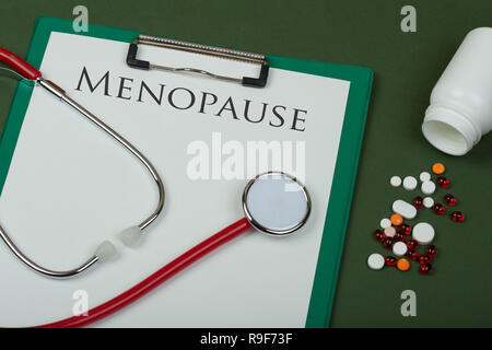 Arzt Arbeitsplatz - Rote Grütze, Pillen, medizinische Flaschen und Zwischenablage mit Text "enopause" auf grünem Papier Hintergrund Stockfoto