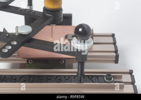 Gravur Gerät Stromabnehmer mit CNC-graveur mit Buchdruck Alphabet auf weißem Hintergrund Stockfoto