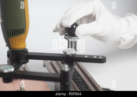 Arbeiter Hände an Gravur Gerät Stromabnehmer mit CNC-graveur mit Buchdruck Alphabet auf weißem Hintergrund Stockfoto