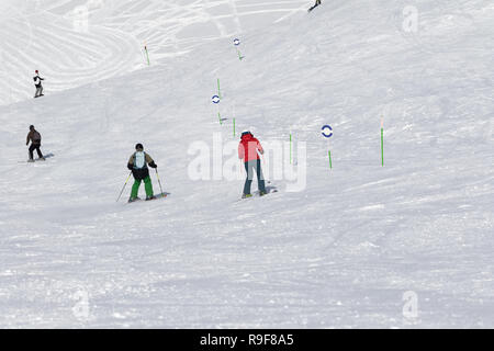 Skifahrer und Snowboarder bergab auf verschneiten Ski am sonnigen Tag verfolgen. Kaukasus Berge im Winter, Georgien, Region Gudauri. Stockfoto