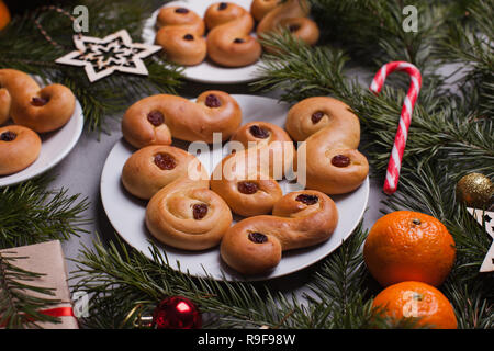 Traditionelle schwedische Weihnachten Safran Brötchen (lussebulle oder lussekatt). Schwedische Weihnachten. Dunkler Hintergrund, Weihnachten Dekoration Stockfoto