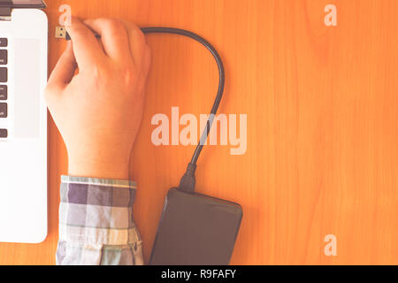 Hand verbindet eine externe HDD-Kabel zum Laptop für die Wiederherstellung von Daten Stockfoto