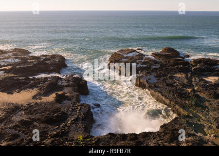 Die Wellen in einem wassereinlass Pausen gegen die Felsen in Cape Perpetua Scenic Area, Oregon, USA Stockfoto