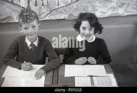 1950, historische, Grundschulkinder, Langbourne School, England, UK. Bild zeigt einen Jungen und Mädchen neben einander sitzen an einem Zweisitzer Holz- Schule Schreibtisch mit ihrer Klasse arbeiten. Stockfoto