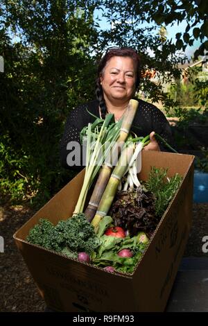 Mitbegründer und Geschäftsführer Maria Alonso zeigt eine typische CSA-Box von produzieren, um Mitglieder der Gemeinschaft an der organischen Gemeinschaft unterstützt Garten und Bauernhof in einem Einkommensschwachen städtischen Gemeinschaft November 13, 2018 in Ontario, Kalifornien. Das US-Ministerium für Landwirtschaft, natürliche Ressourcen Naturschutz Service und Redlands Bezirk Naturschützer Tomas Aguilar-Campos arbeiten eng mit der lokalen Gemeinschaft zu lokalen Bio-Produkten für alle, unabhängig von Einkommen unterstützen. Stockfoto