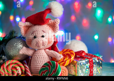 Lustige Grußkarte mit ins neue Jahr 2019. Rosa Schwein mit Lutscher closeup auf Hintergrund mit Beleuchtung. Stockfoto