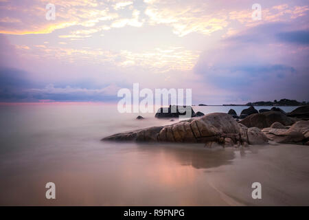 Sonnenaufgang an der Insel Bintan. Sand meer himmel wolken und Steine Stockfoto