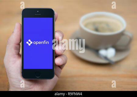 Ein Mann schaut auf seinem iPhone die zeigt die Openfin Logo (nur redaktionelle Nutzung).