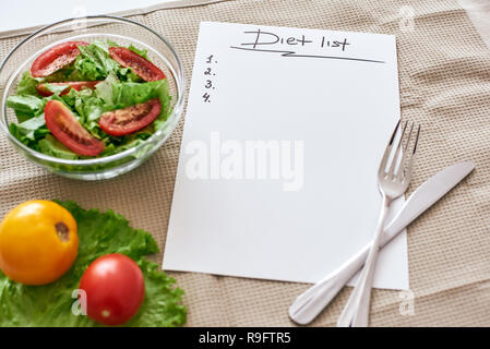 Diät Liste. Vorbereitung Rezeptur zu schreiben. Notebook, Tischdecke, Messer und Gabel liegen auf dem Tisch. Frisches Gemüse sind auf dem Tisch. 7/8-Foto Stockfoto