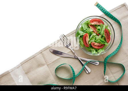 Diät essen. Vorbereitung von Salat, Tischdecke, Messer und Gabel zu essen liegen auf dem Tisch. Frisches Gemüse gemischt im Salat auf den Tisch. 7/8-Foto Stockfoto