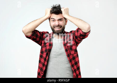 Schöner Mann drücken die Hände auf den Kopf und ballte Zähne Panik in perplex Situation Stockfoto