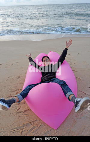Man entspannende in rosa Lazy bag am Strand Stockfoto