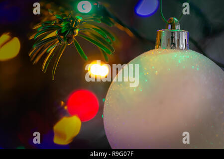 Nahaufnahme von einem weißen, Frosty christbaumkugel vor bunte Lichter am Weihnachtsbaum Stockfoto