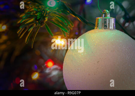 Nahaufnahme von einem weißen, Frosty christbaumkugel vor bunte Lichter am Weihnachtsbaum Stockfoto