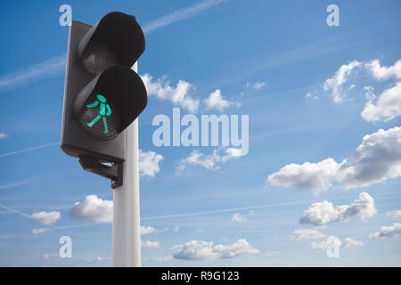 Ein Verkehr grünes Licht für Fußgänger gegen den Himmel. Stockfoto