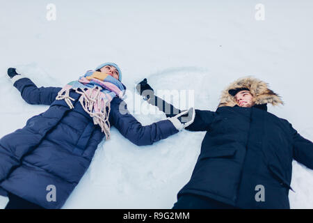 Schöne liebevolle Paar Beschneiung Engel im Winter Wald im Schnee liegen. Glückliche Menschen Spaß im Freien Stockfoto