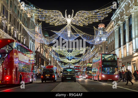 Rote Doppeldeckerbusse fahren Sie unter funkelnden Weihnachtsbeleuchtung entlang der schönsten Einkaufsstraßen der Regent Street. Stockfoto