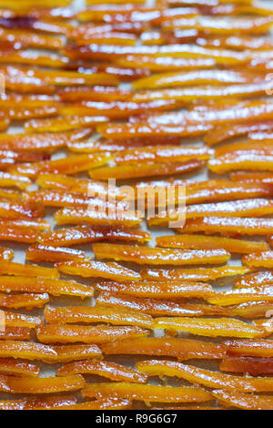 Orangeat, in Zuckersirup mit Vanille und Ingwer gekocht, trocknen auf Pergamentpapier. Selektive konzentrieren. Stockfoto