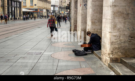 Zagreb, Kroatien, November 2018 - Street Performer seine Gitarre Tuning bei Ilica Straße mit Fußgängern und Geschäften Stockfoto