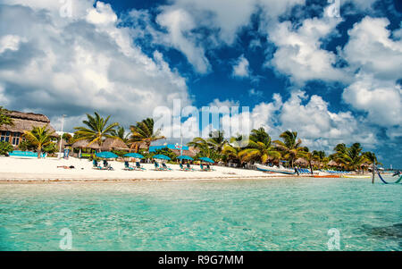 Costa Maya, Mexiko - 01. Februar 2016: Strand mit grünen Palmen, Schirme auf Sand. Meer oder Ozean Wasser an der Costa Maya, Mexiko. Tropical Resort an einem sonnigen Tag an bewölkten Himmel. Sommer Urlaub, Reisen. Stockfoto