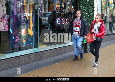 London, Großbritannien. 23 Dez, 2018. Ein Paar gesehen, Weihnachten Jumper an der Londoner Oxford Street. letzte Weihnachtskäufer nutzen die Vorteile der vorweihnachtlichen Schnäppchen auf der Oxford Street in London. Weniger Kunden wurden Einkaufen in hohen Großbritanniens Straßen als on-line-Verkäufe erhöhen berichtet. Credit: Dinendra Haria/SOPA Images/ZUMA Draht/Alamy leben Nachrichten Stockfoto