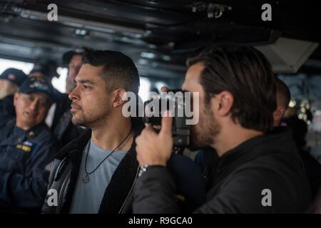 USS Stennis Air Craft Carrier, Oman. 23 Dez, 2018. Schauspieler Milo Ventimiglia, rechts, nimmt ein Foto als Wilmer Valderrama, Mitte, schaut bei einem Besuch auf der Brücke der Flugzeugträger USS John C Stennis vor der Teilnahme an der Generalstabschefs USO Christmas Show für bereitgestellte Service Mitglieder Dezember 23, 2018 im Persischen Golf. Unterhaltungskünstler in diesem Jahr gehören Schauspieler Milo Ventimiglia, Wilmer Valderrama, DJ J Dayz, stärkste Mann auf Erden Matt Fraser, 3-mal Olympiasieger Shaun White, Country Music Singer Kellie Pickler und Komiker Jessiemae Peluso. Credit: Planetpix/Alamy Live Neue Stockfoto