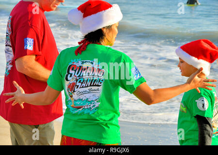 Cocoa Beach, Florida, USA. Dezember 24, 2018 Für die letzten neun Jahre, bevor Santa liefert Spielwaren und Geschenke, er brechen weg, einige Wellen in Cocoa Beach am Heiligabend Morgen zu erwischen. Die Surfing Santa's Event ist eine jährliche Cocoa Beach Tradition, bringt Hunderte Surfer gekleidet wie santa zu einem der berühmtesten Strände der Welt. Foto: Julian Porree/Alamy leben Nachrichten Stockfoto