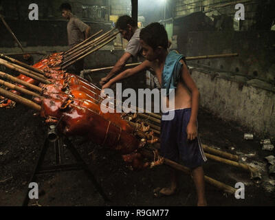 Quezon City, Philippinen. 15 Mär, 2012. Ein Knabe, wodurch die überschüssige Fell am Körper der Spanferkel zu entfernen. Die Gattungen werden dann zum Verkauf als ein traditionelles Essen für die Weihnachten feiern werden. Credit: Josefiel Rivera/SOPA Images/ZUMA Draht/Alamy leben Nachrichten Stockfoto