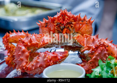 Nahaufnahme von lecker lecker gekocht Frisch rote Königskrabben auf Metall Teller mit Zitrone, gruene Sauce zubereitet. Konzept teures Essen, Schmuggel, vip-Lieferung Stockfoto