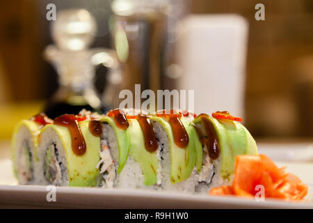 Closeup Shogun Sushi Roll mit Avocado, Erdbeere, teriyaki Sauce, Sesam, Wasabi, Ingwer, weisse japanische Platte, Sojasauce, weiße Servietten, Glas ... Stockfoto