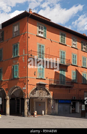 Typische grüne Fensterläden über Windows von grossen roten Ocker Gebäude mit Erdgeschoss Bögen und oberen Balkone an der Ecke ein Quadrat in Pisa, Italien Stockfoto