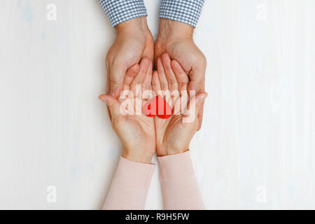 Nahaufnahme der Hand eines Mannes und einer Frau ein Herz zusammenhalten. Ansicht von oben. Konzept der Valentinstag gefeiert. Stockfoto