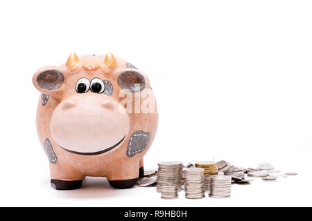 Sparschwein und Münzen bis auf weißem Hintergrund gestapelt. Stockfoto