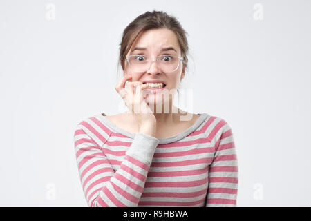 Besorgt weiblichen sieht nervös beißt finger Nägel, Uhren, Horror Film. Stockfoto