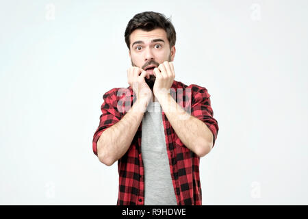 Junger Mann, Mund, Hände und runde Augen erleben tiefes Erstaunen und Angst Stockfoto