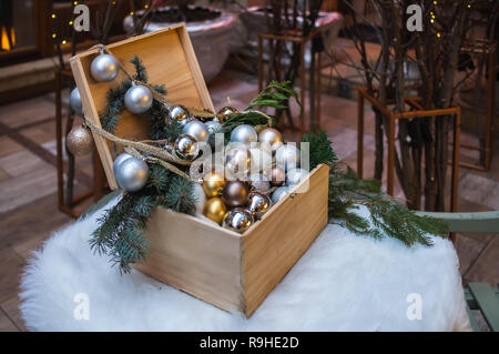 Ein offener Kasten mit Weihnachten Spielzeug ist auf dem runden Tisch. Die Tabelle ist mit weißer Haut gelegt. Stockfoto