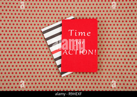 Notizblöcke mit Text "Zeit zum Handeln!" auf Handwerk Papier Hintergrund in Rot Polka Dots Stockfoto