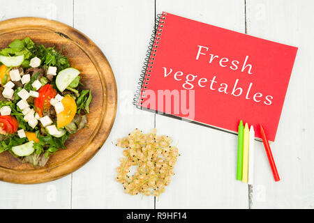 Diät plan-Salat mit frischem Gemüse und Notizblock mit Text "Frisches Gemüse" auf einem weißen Tisch Stockfoto