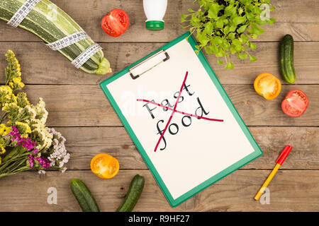 Diätplan - Mark Squash, Zwischenablage mit Text "Kein Fast Food', Gemüse und Maßband auf braune Holztisch Stockfoto