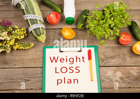 Diätplan - Mark Squash, Zwischenablage mit Text "Weight Loss Plan', Gemüse und Maßband auf braune Holztisch Stockfoto