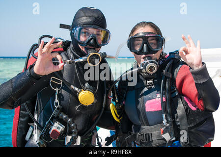 Zwei glückliche Taucher im Neoprenanzug und Masken mit Octopus in mouthes auf dem Hintergrund der azurblauen Meer OK angezeigt. Happy Girls in Neoprenanzüge. tauchen. Tauchen. Stockfoto